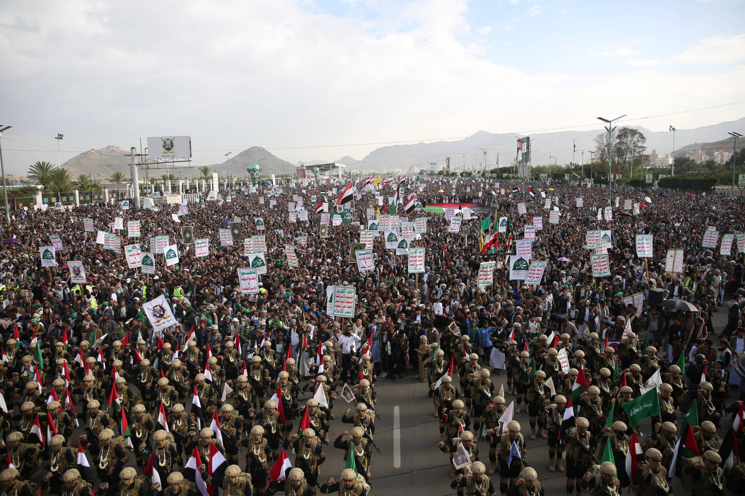 Les troupes armées sont suivies par une foule de soutien.
