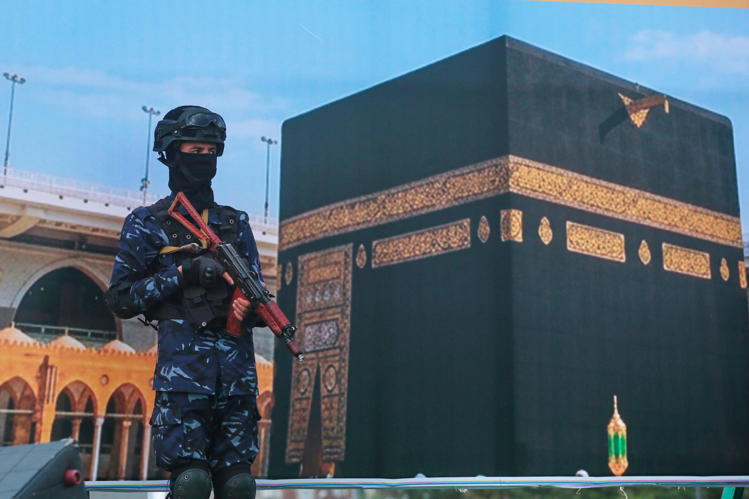 Un soldat des rebelles houthis du Yémen se tient devant une banderole géante représentant la Kaaba, lors d'un rassemblement organisé pour protester contre l'accusation portée par l'Arabie saoudite selon laquelle les Houthis auraient pris pour cible le lieu le plus sacré de l'islam, à Sanaa le 18 septembre 2026.