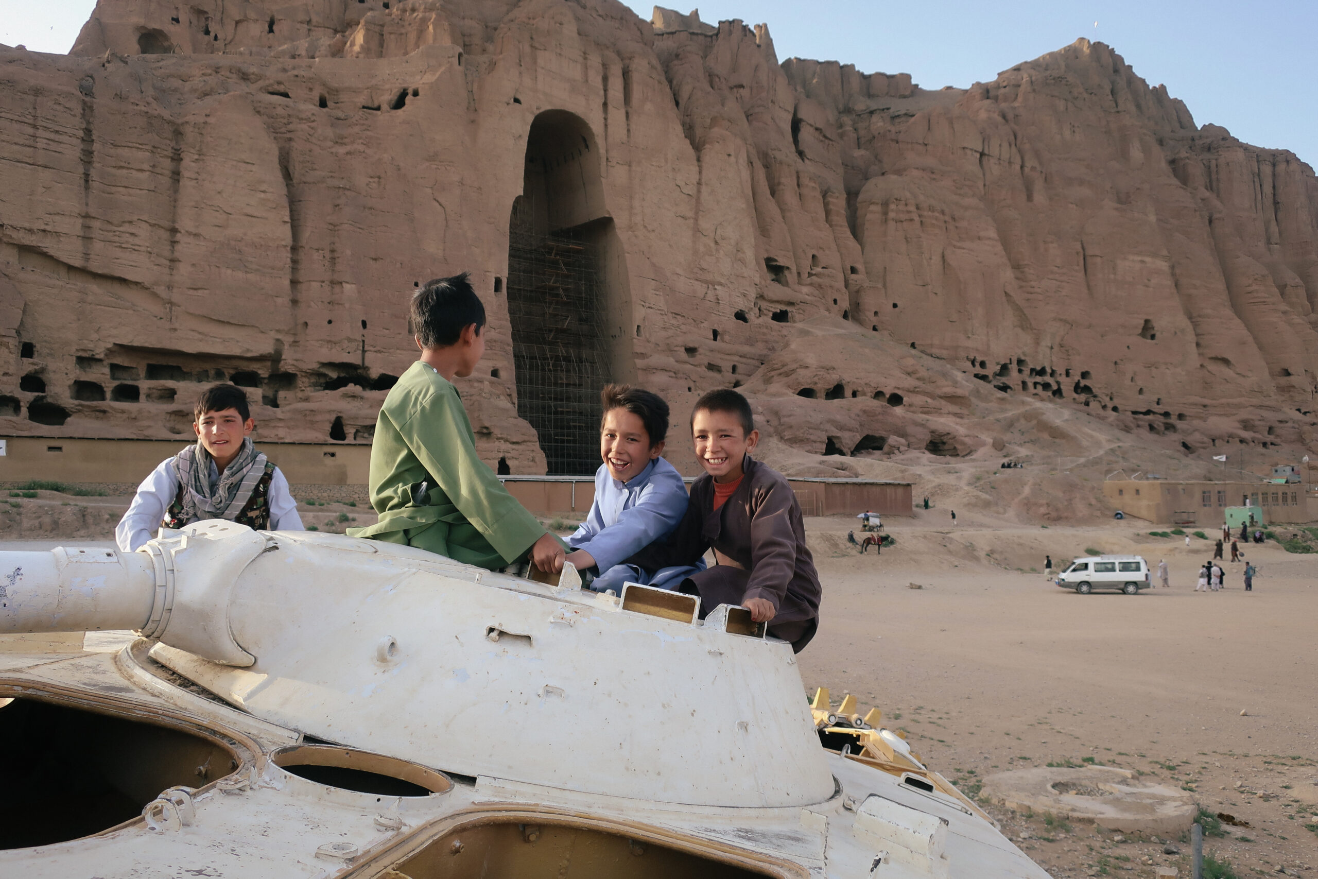 Dei bambini sulla torretta di un carro armato sovietico, di fronte alla nicchia vuota del Grande Buddha di Bamyan, mettono in scena la «pacificazione» talebana. © Nicolò Sancassiani.