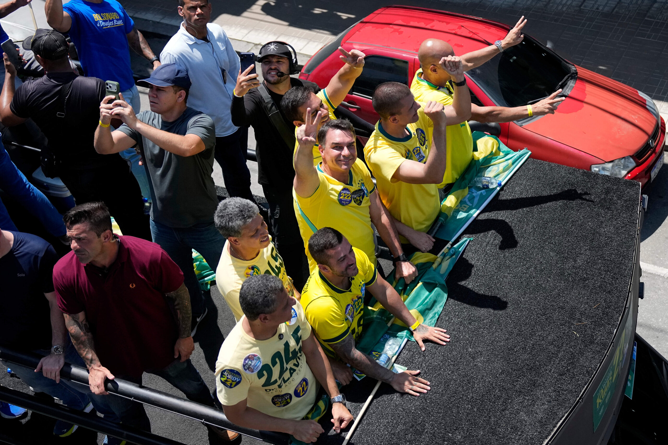 Con il braccio teso, Flávio Bolsonaro fa un gesto con la mano a forma di «V» per indicare la «Vittoria».