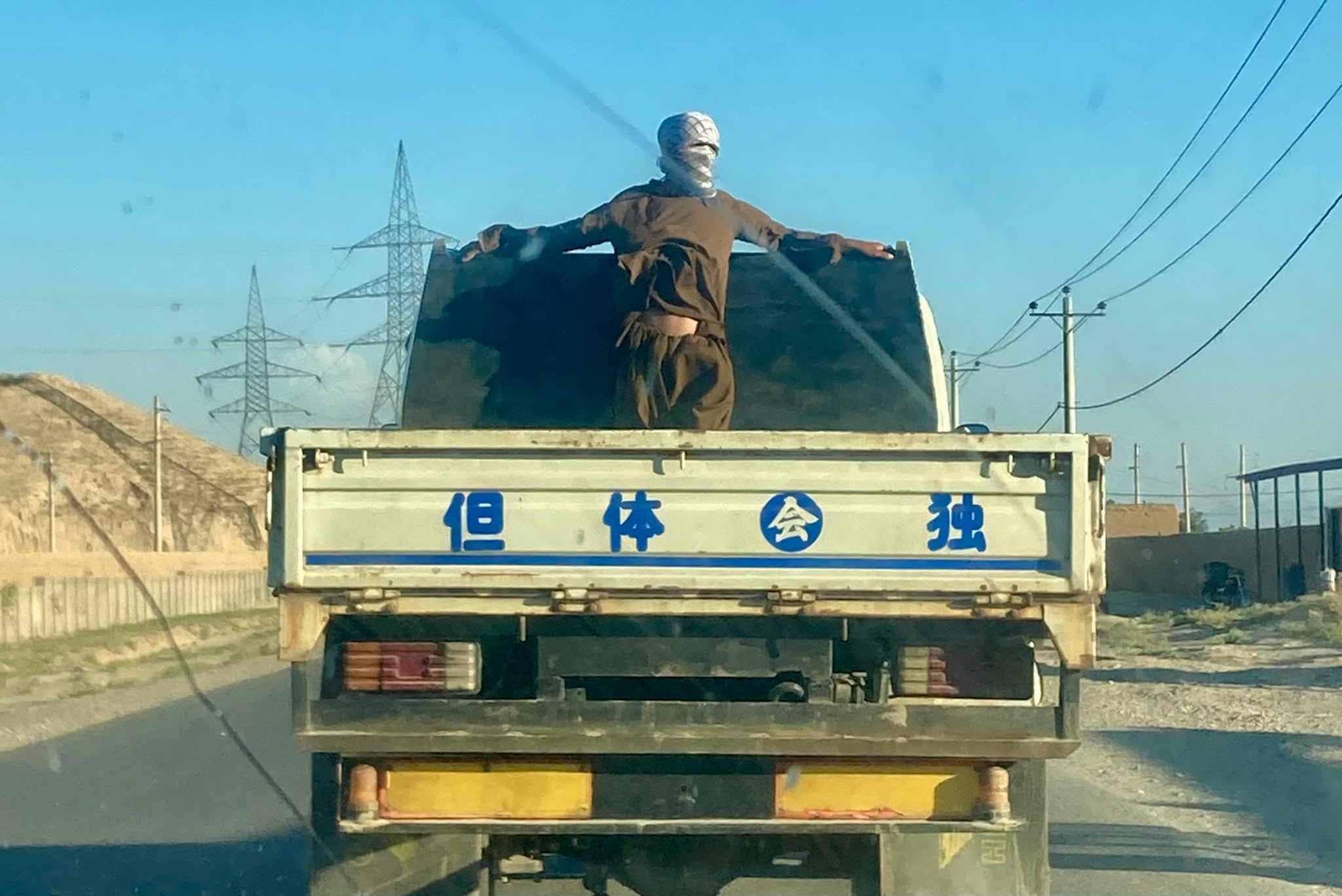 Un uomo in piedi sul retro di un camion proveniente dall'Asia. Veicoli e tessuti cinesi invadono i mercati da Kabul a Herat © Nicolò Sancassiani.